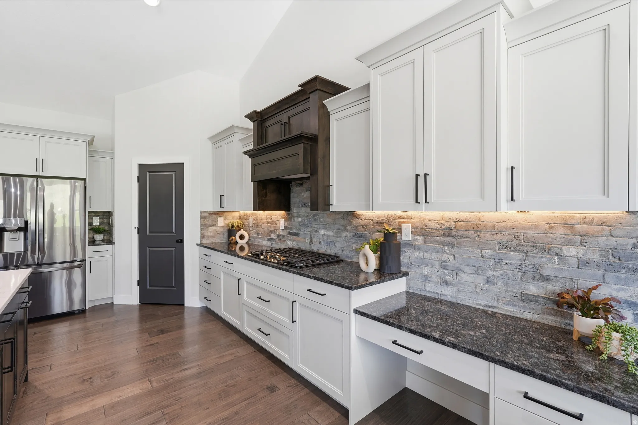 Kitchen with stainless steel appliances, dark granite countertops, white cabinets, and backsplash