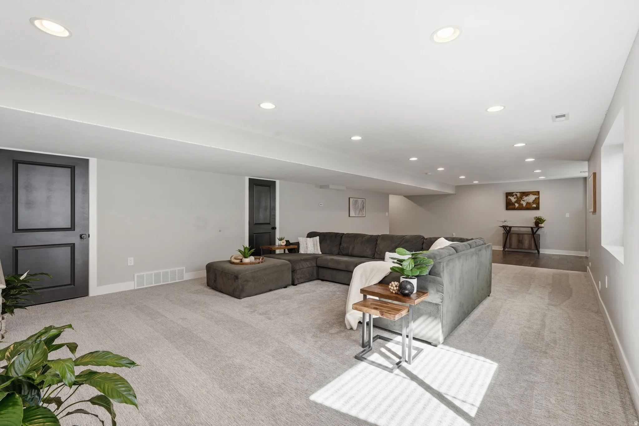 Basement living area with recessed lighting and light carpet
