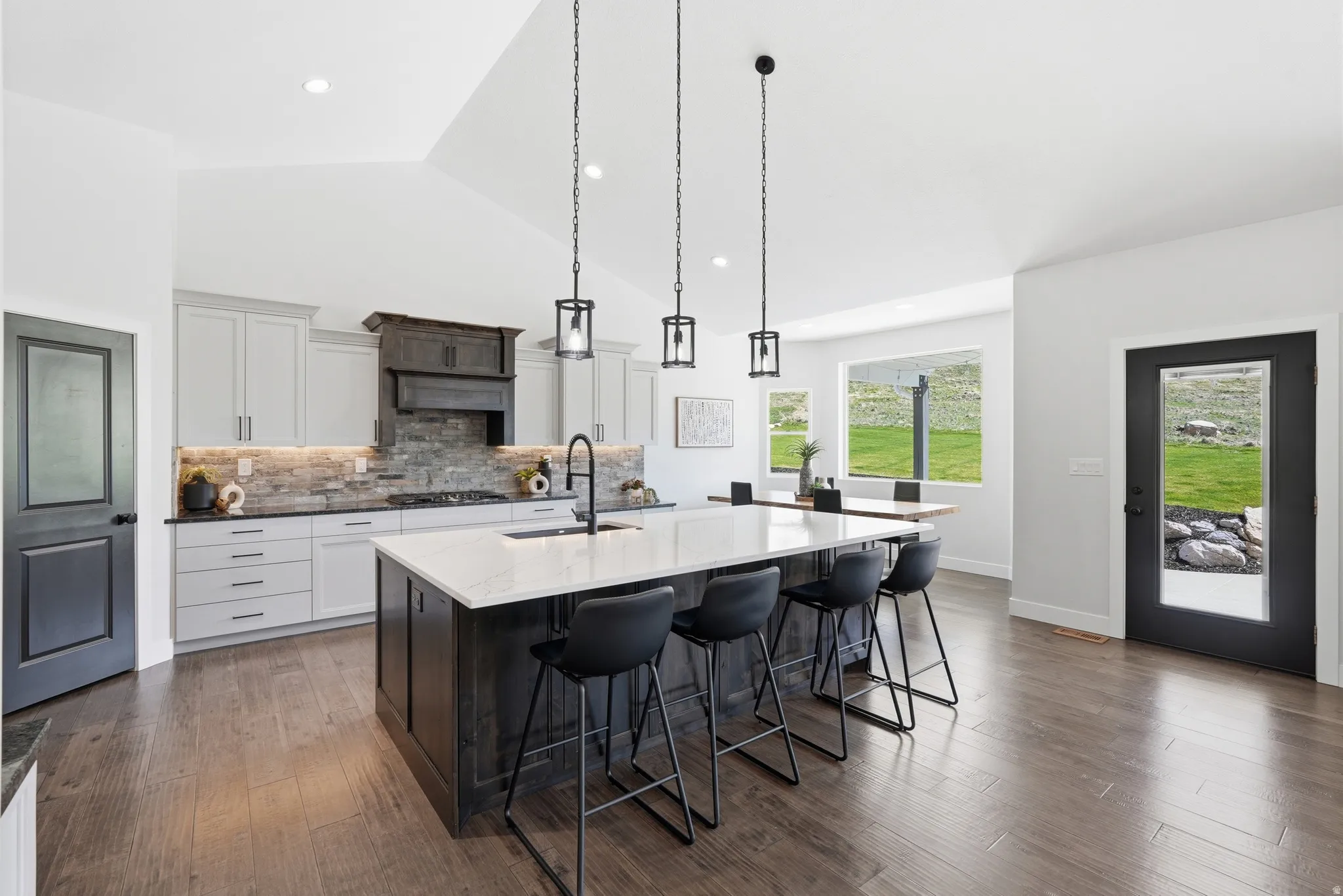 Dual tone kitchen featuring two tone color scheme, granite countertops, a breakfast bar, tasteful backsplash, and hardwood flooring