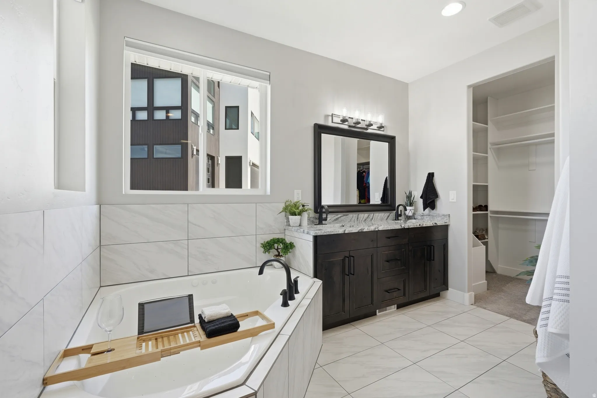 Primary bathroom featuring double vanity, a garden tub, and 2 spacious walk-in closets