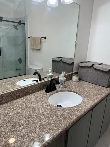 Full hall bathroom with vanity and a marble finish shower