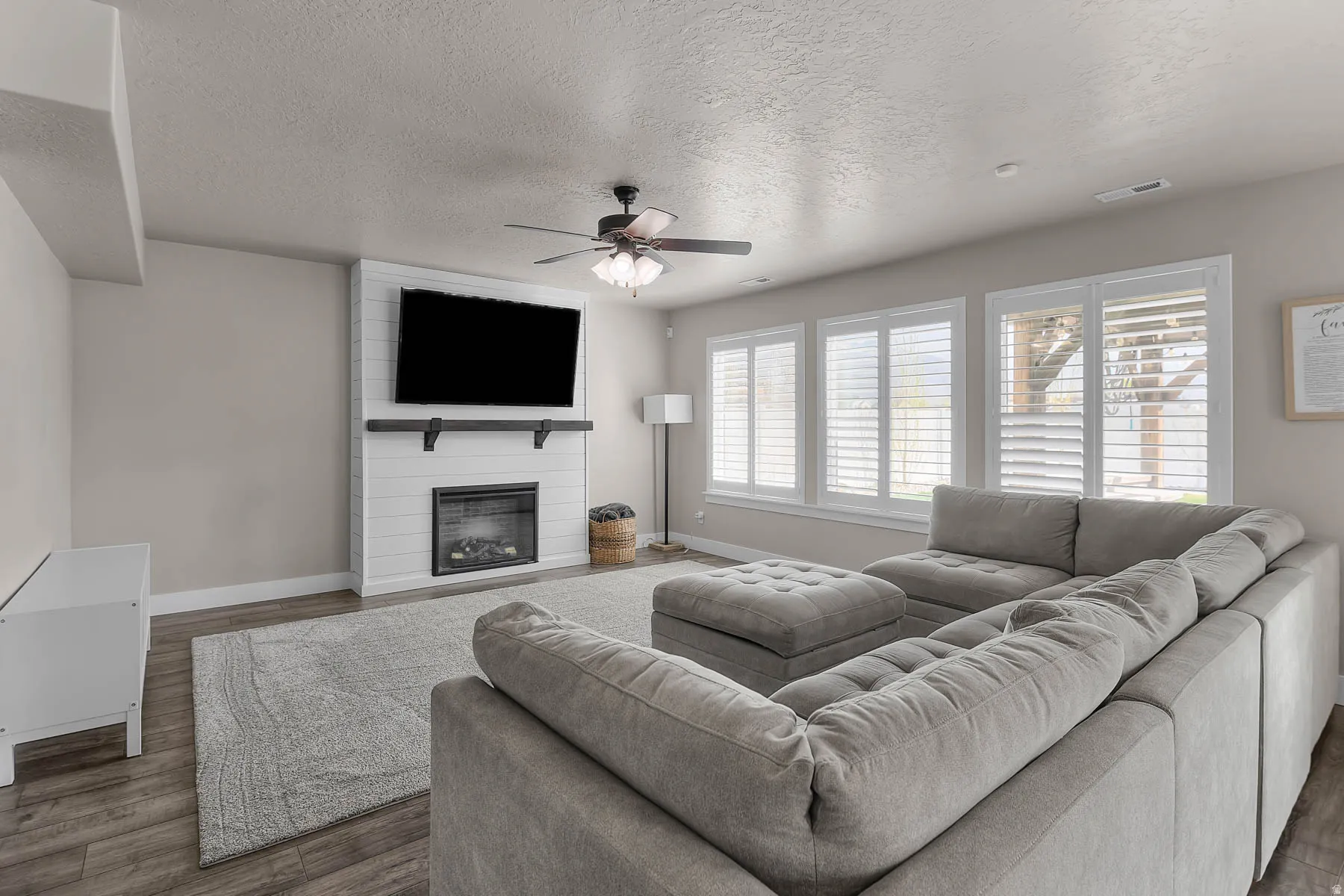 Living area featuring a textured ceiling, a fireplace, wood finished floors, and ceiling fan
