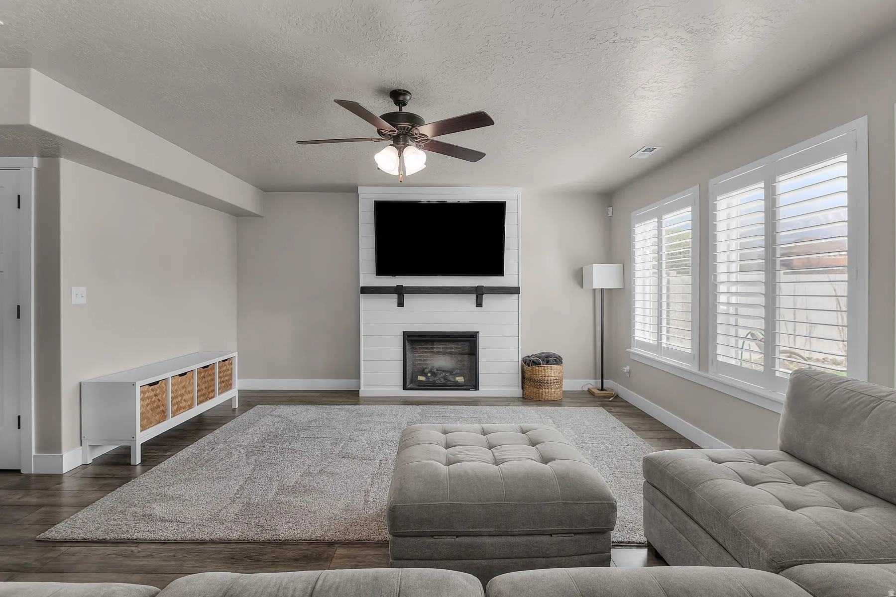 Living area featuring ceiling fan, dark wood-type flooring, a fireplace, and a textured ceiling