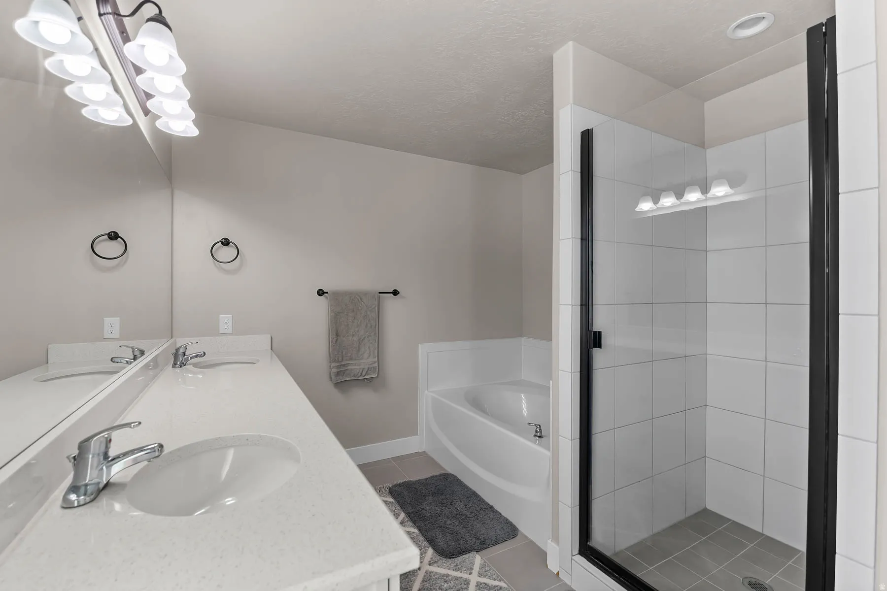 Full bathroom with a garden tub, double vanity, light tile patterned flooring, and a stall shower
