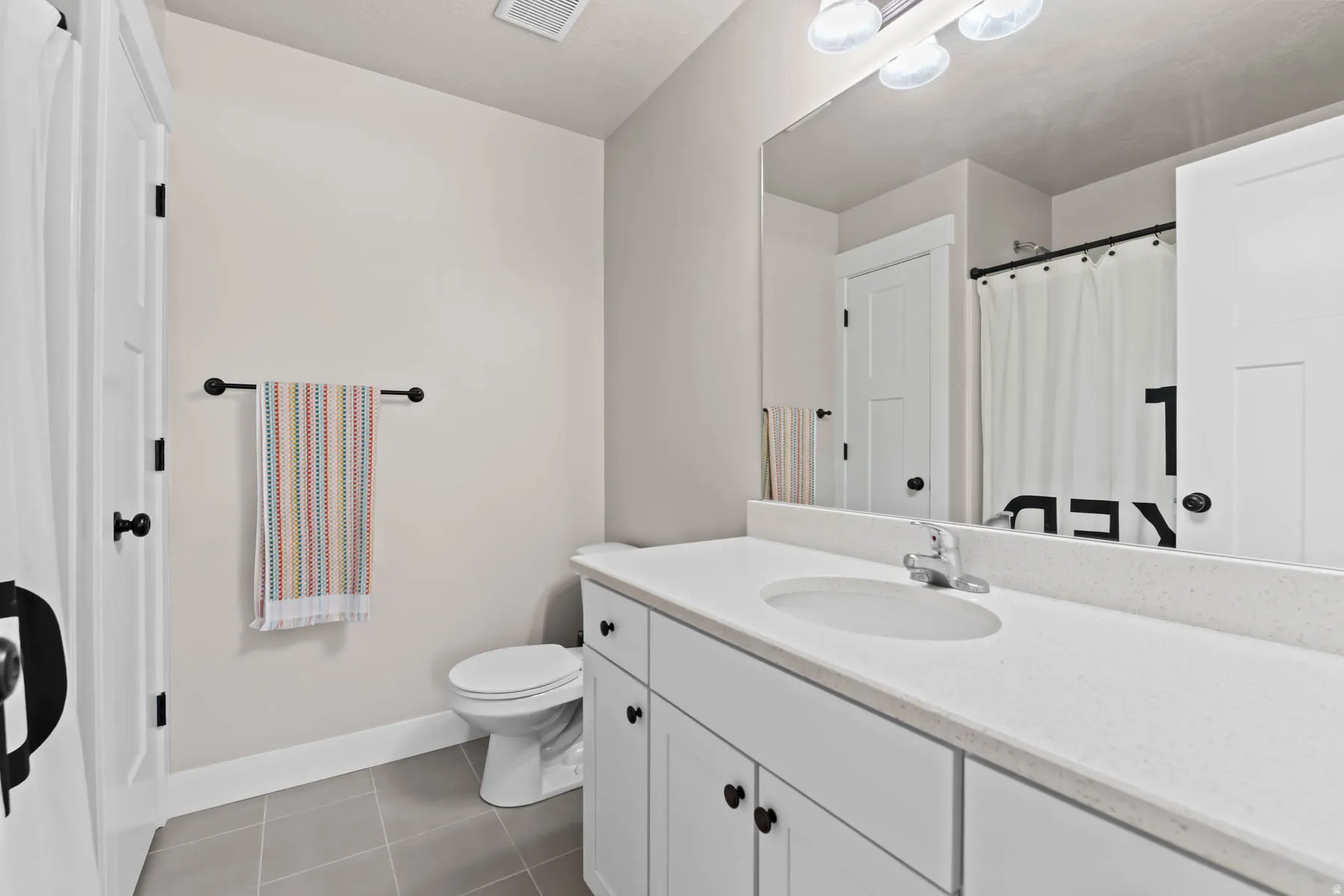 Full bath with vanity, a shower with shower curtain, and dark tile patterned floors