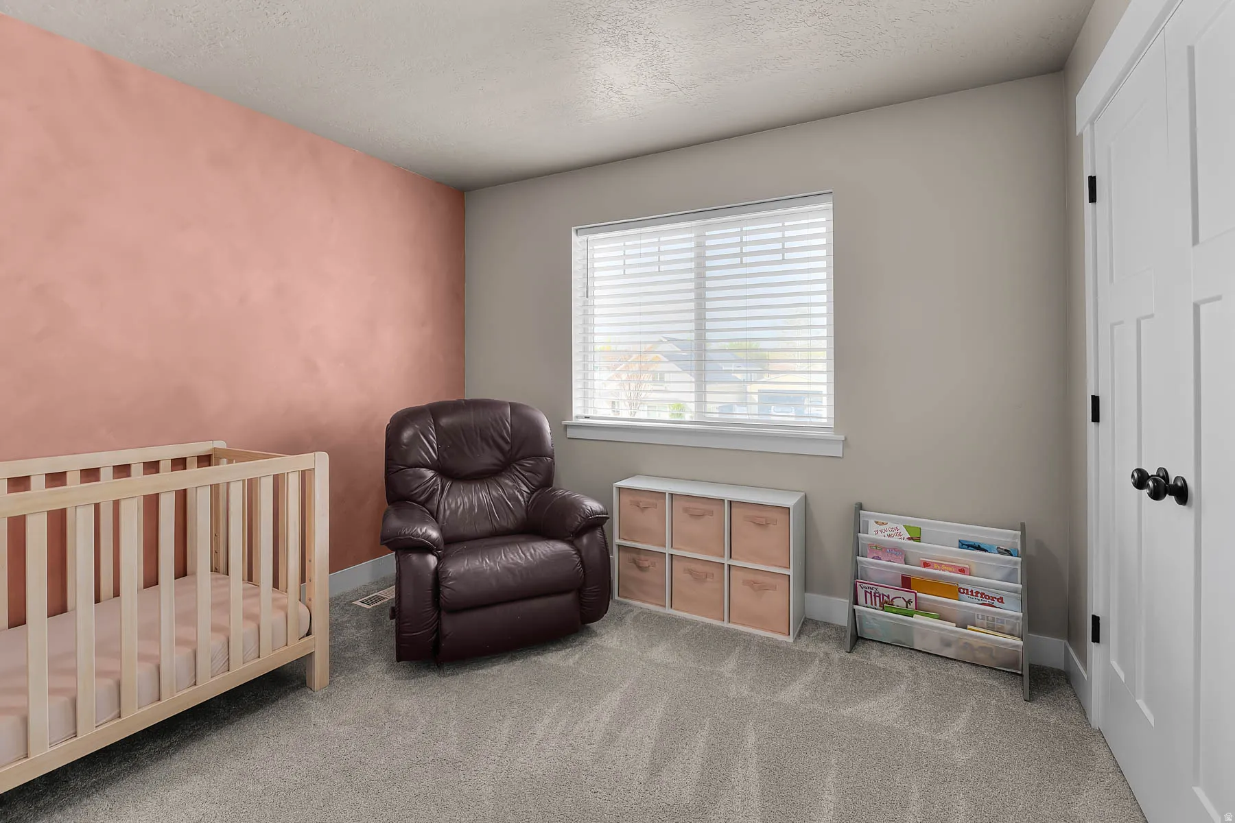 Bedroom with a crib, a textured ceiling, and carpet floors