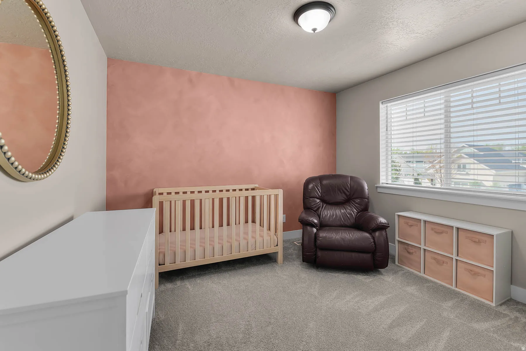 Carpeted bedroom with a crib and a textured ceiling
