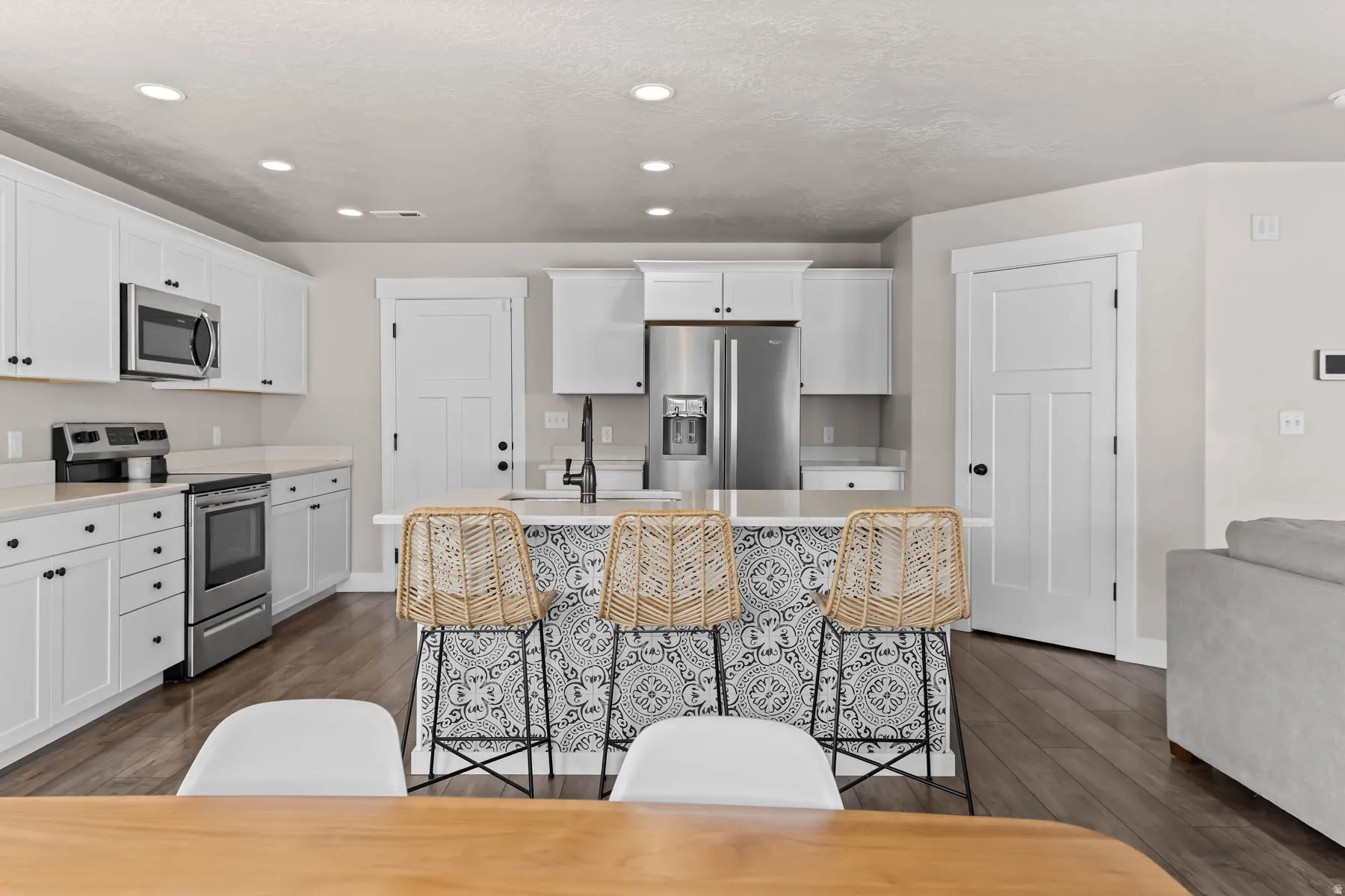 Kitchen featuring stainless steel appliances, dark wood-type flooring, white cabinets, and recessed lighting