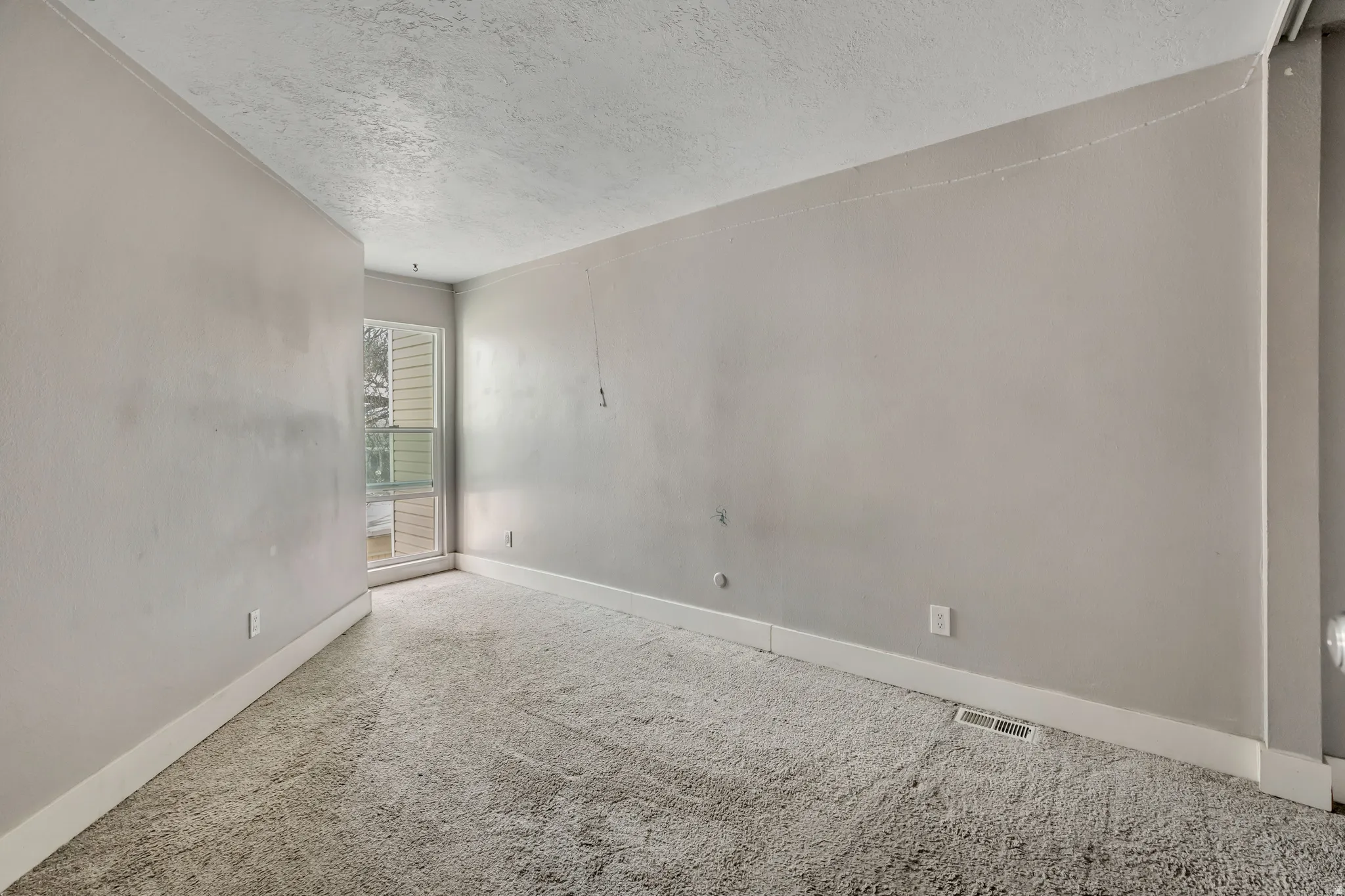 Carpeted empty room with baseboards and a textured ceiling