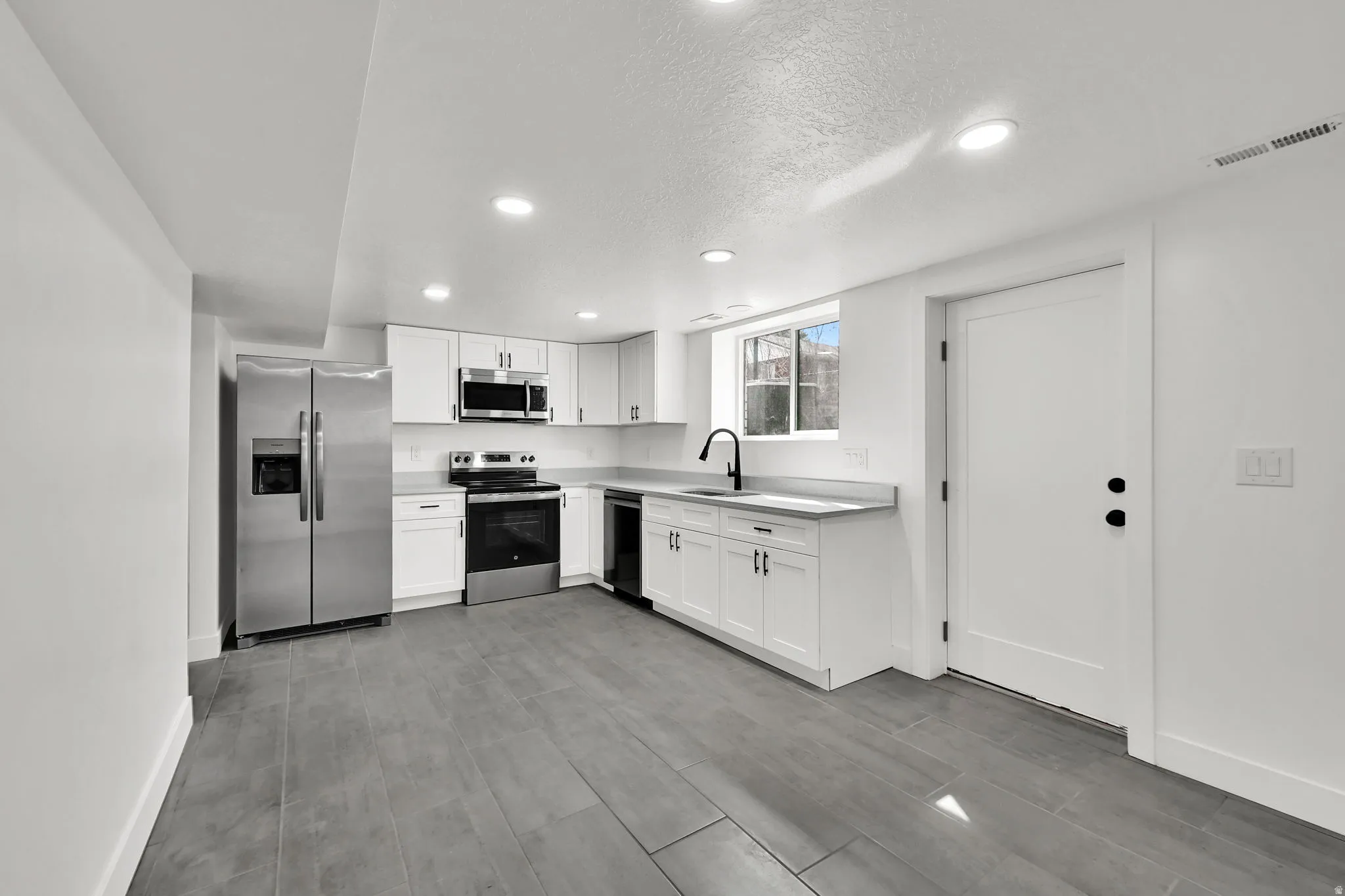 Kitchen featuring stainless steel appliances, recessed lighting, light countertops, white cabinets, and light wood-style flooring