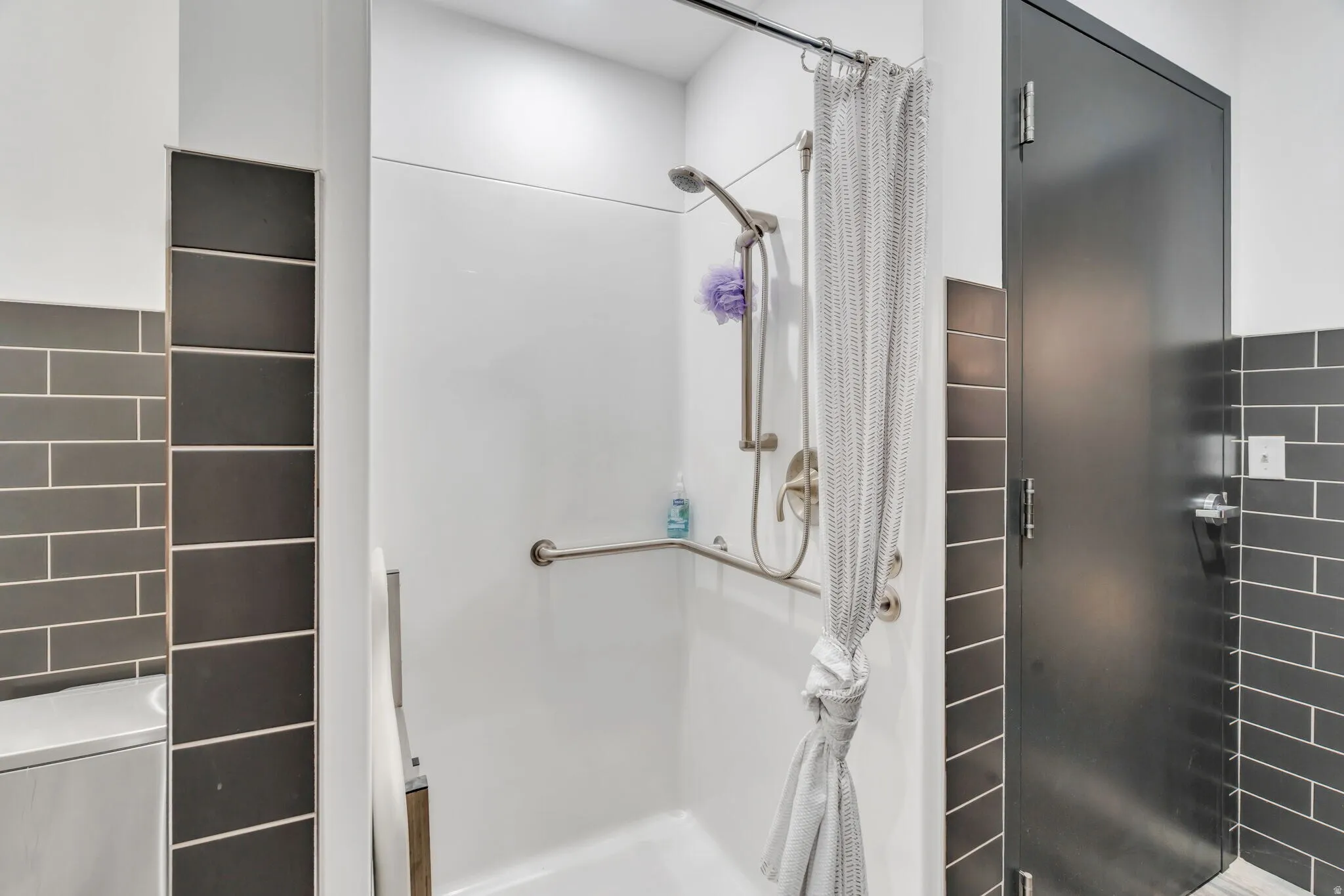 Bathroom featuring a stall shower and tile walls