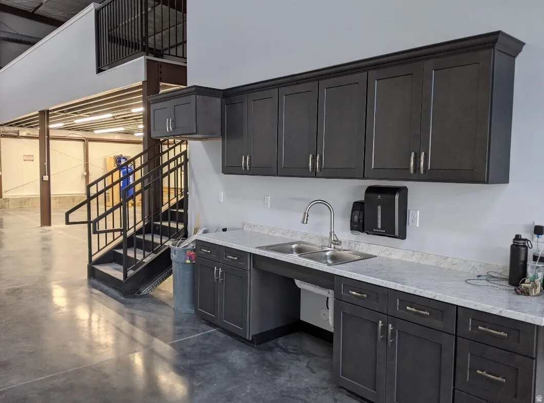 Kitchen with finished concrete floors, dark cabinetry, and a high ceiling