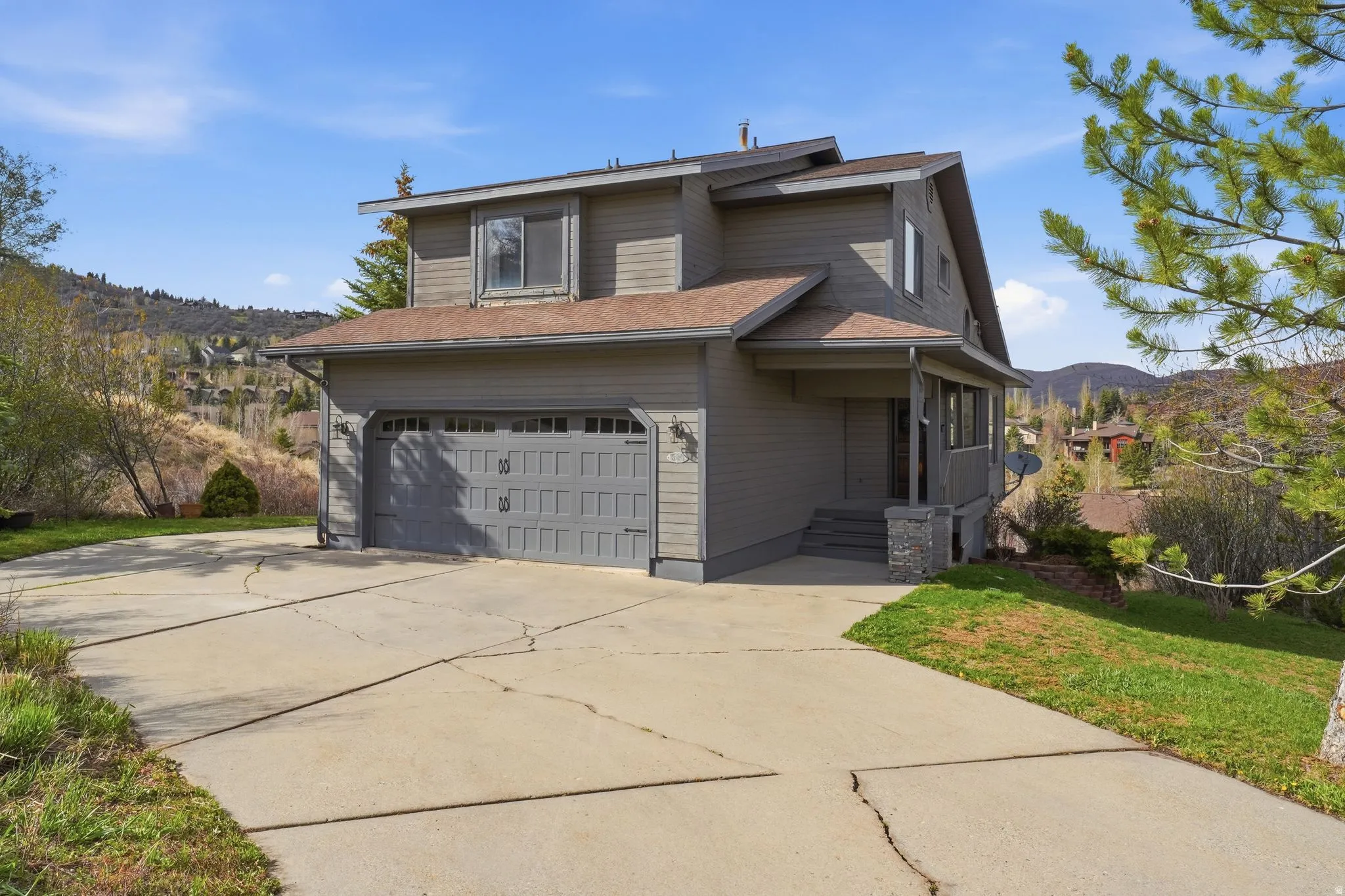Traditional-style house featuring concrete driveway, a mountain view, a front lawn, and an attached garage