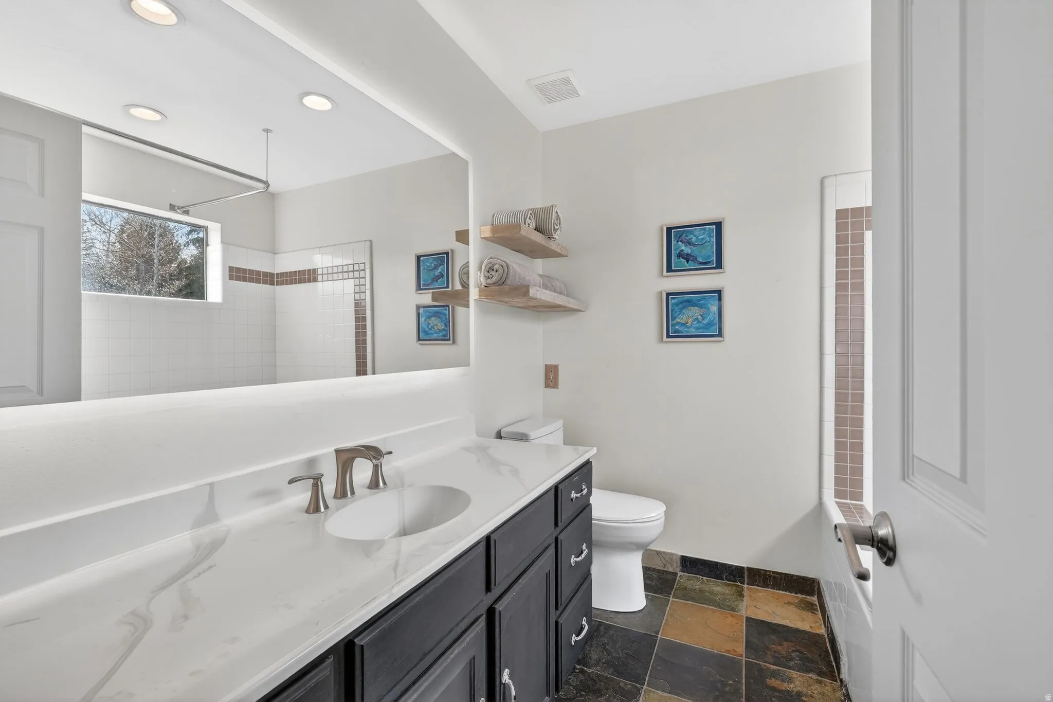 Full bath featuring vanity, a tile shower, dark stone finish floors, and recessed lighting
