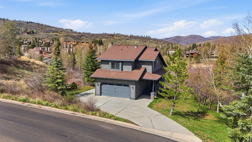 View of front of home featuring a shingled roof, a mountain view, concrete driveway, a garage, and a front yard
