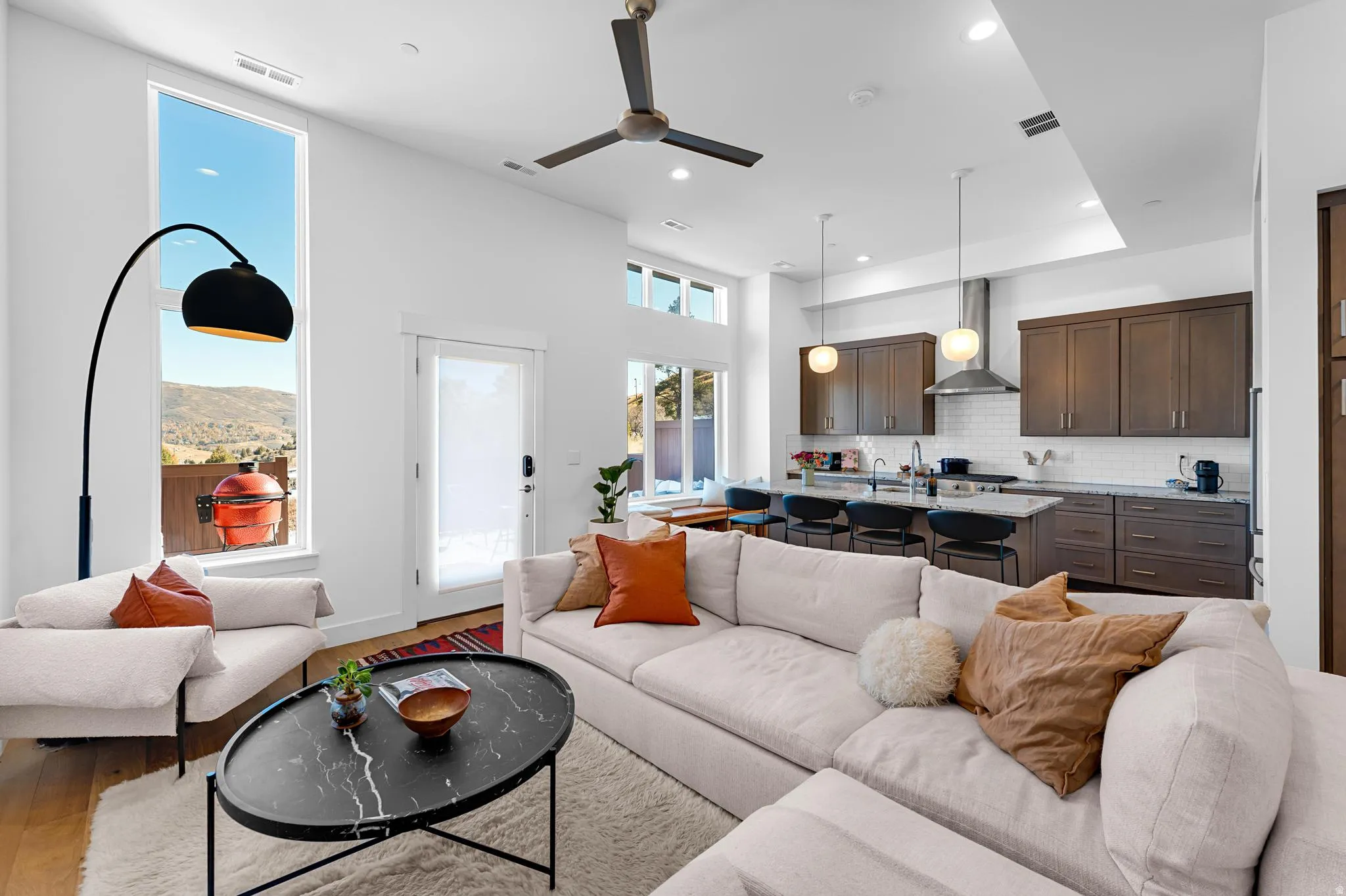 Living area with a ceiling fan, light wood-type flooring, recessed lighting, and a high ceiling