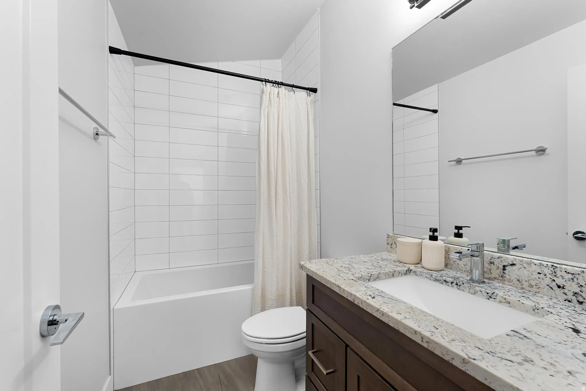 Bathroom with vanity, shower / bath combo, and dark wood-style flooring