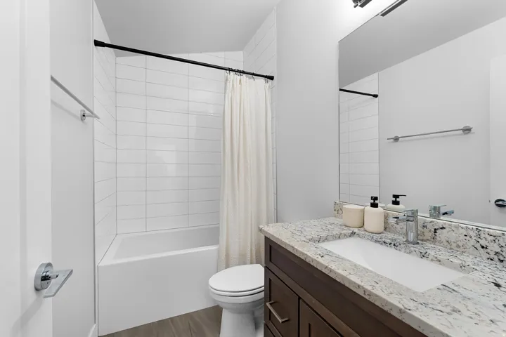 Bathroom with vanity, shower / bath combo, and dark wood-style flooring
