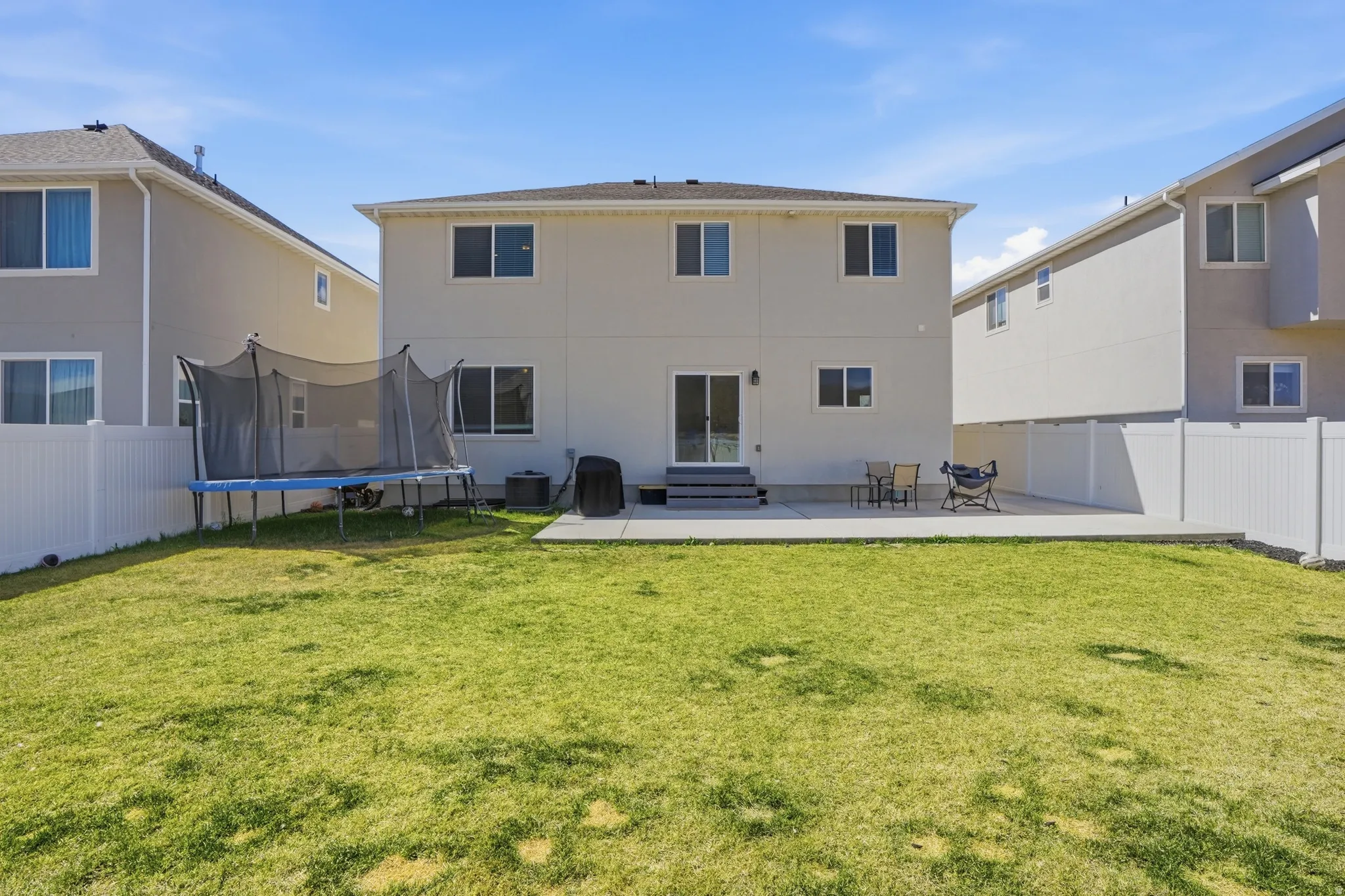 Rear view of property featuring a patio, a fenced backyard, and a trampoline