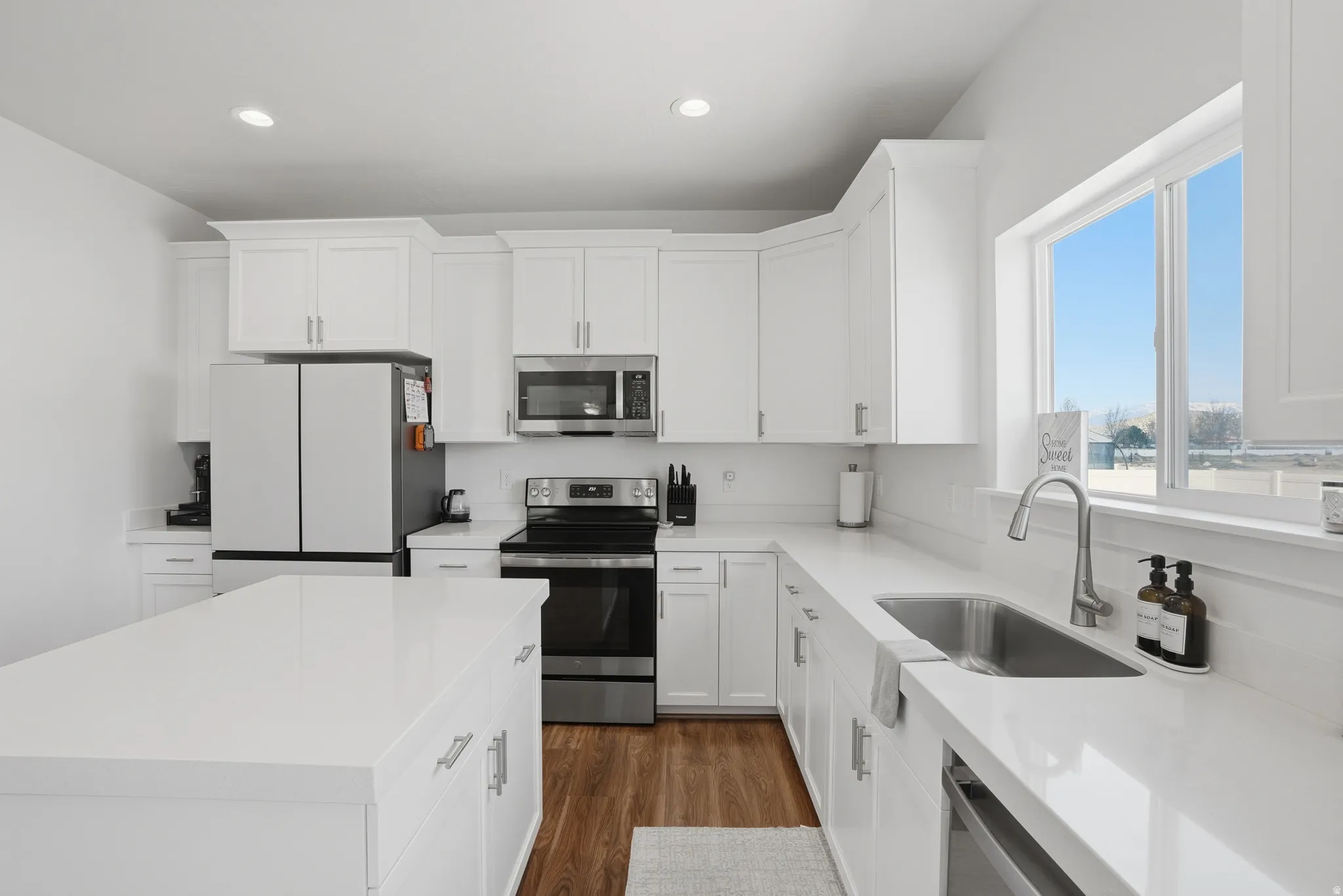 Kitchen with stainless steel appliances, white cabinetry, dark wood-style floors, a center island, and recessed lighting