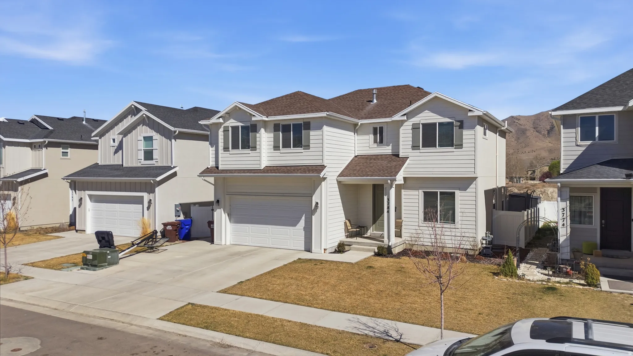 Traditional home with a garage, a residential view, concrete driveway, and a shingled roof