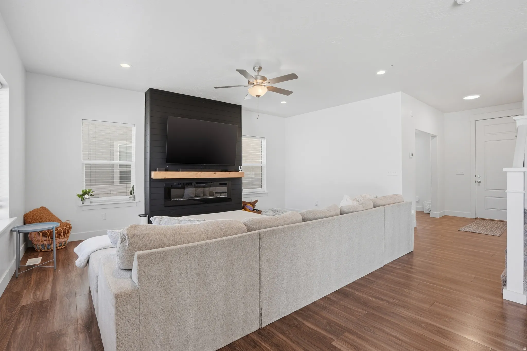 Living area featuring a large fireplace, a ceiling fan, dark wood-style floors, and recessed lighting