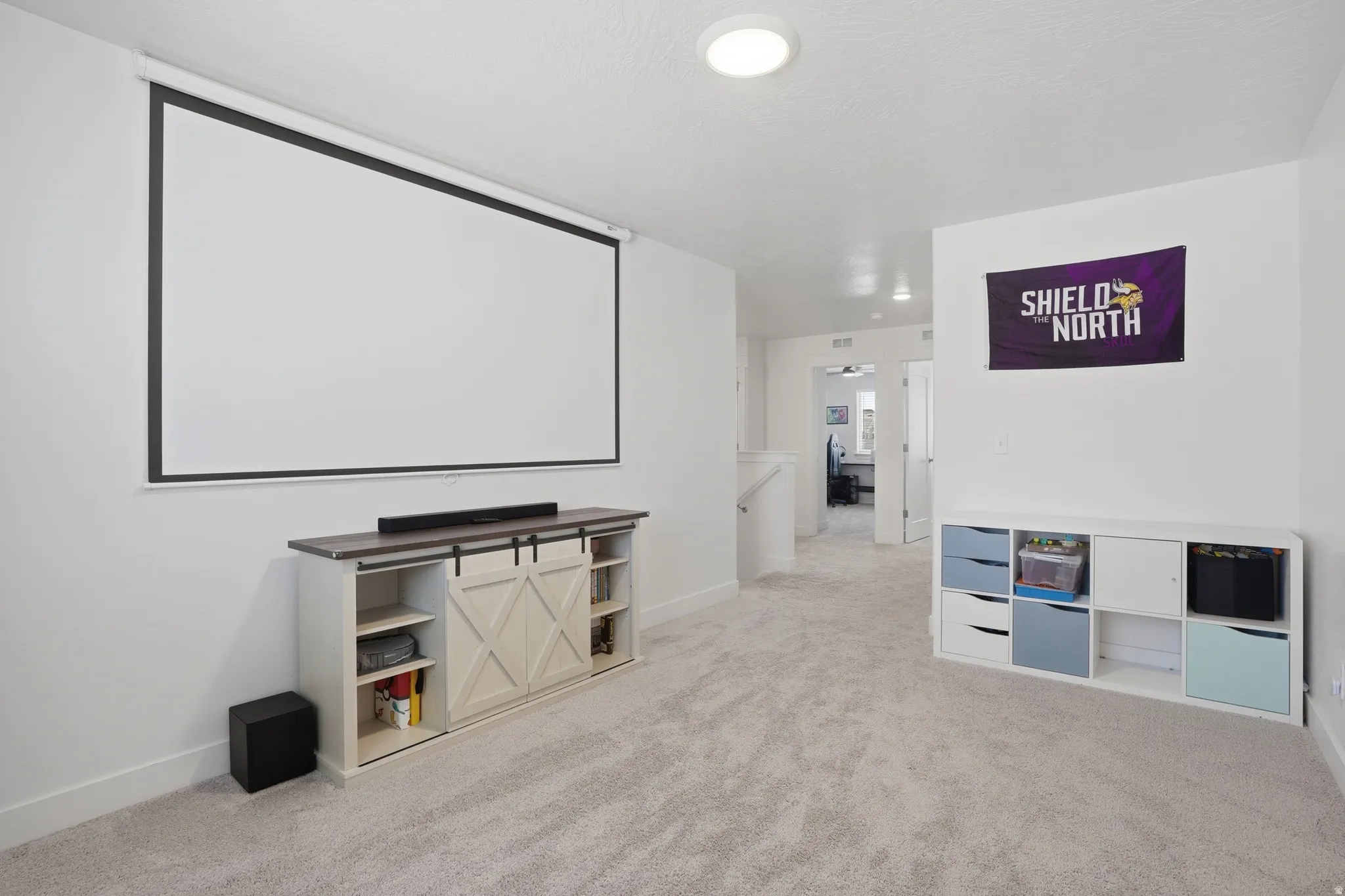 Home theater room featuring light carpet and baseboards