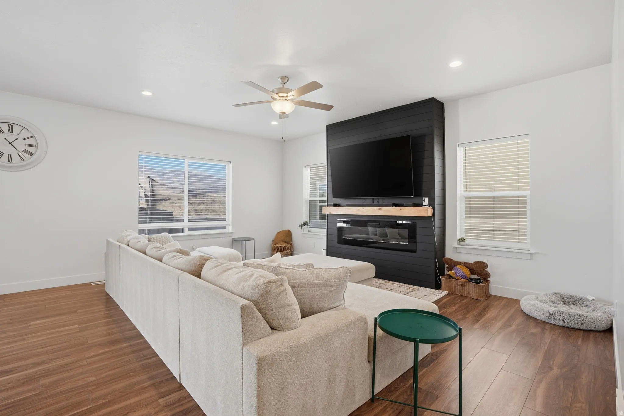 Living area featuring wood finished floors, ceiling fan, recessed lighting, and a fireplace