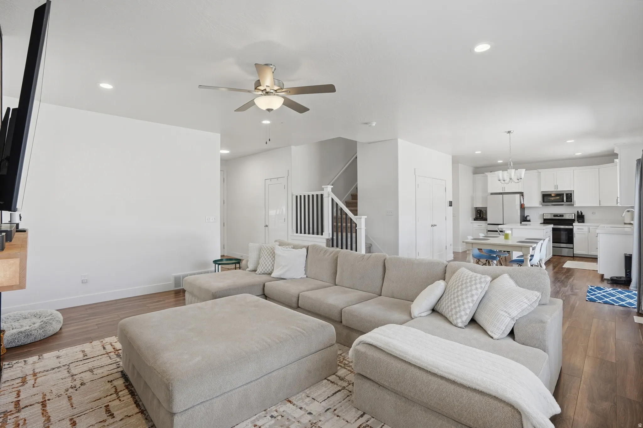 Living room featuring wood finished floors, a ceiling fan, and a chandelier