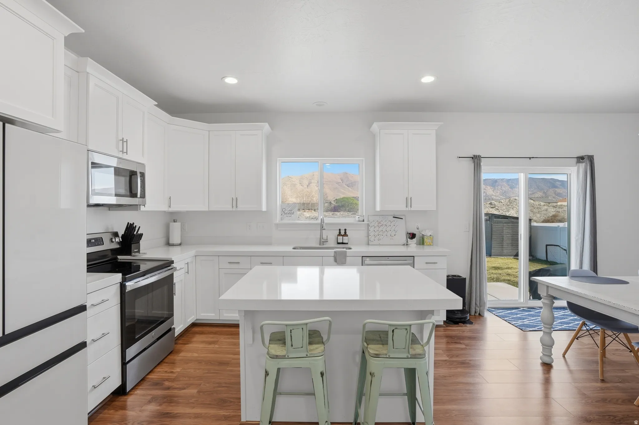 Kitchen featuring a kitchen breakfast bar, stainless steel appliances, a kitchen island, dark wood-style flooring, and recessed lighting