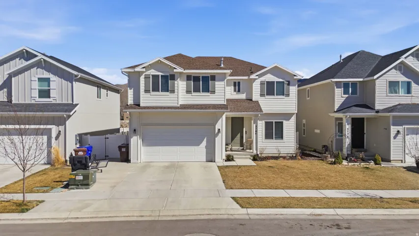 Traditional-style house with an attached garage, concrete driveway, and a shingled roof