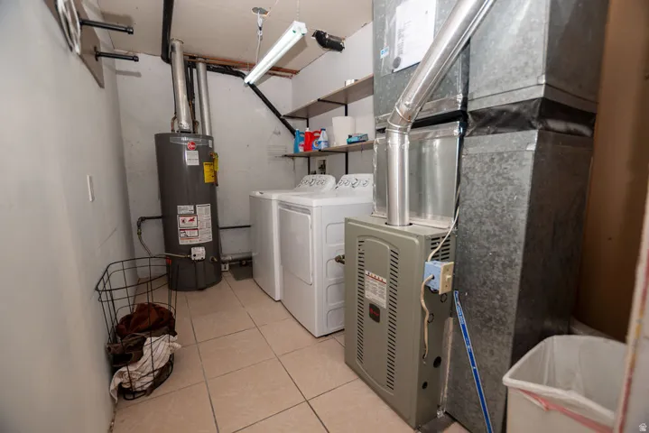 Laundry room featuring gas water heater, heating unit, washer and clothes dryer, and light tile patterned floors