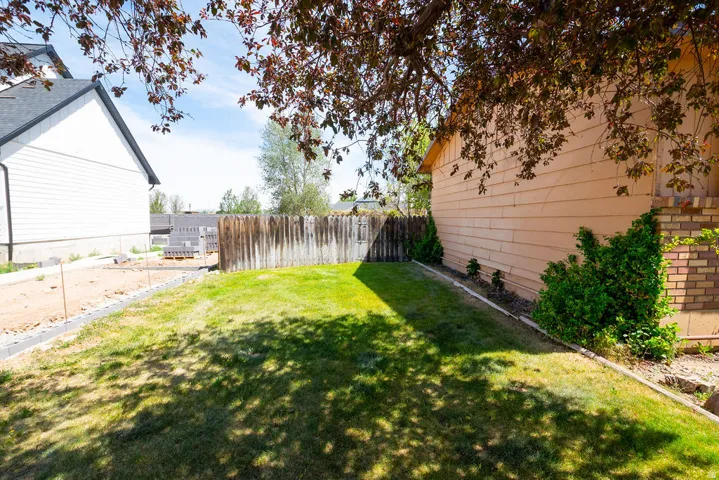 Expansive backyard with a manicured lawn, bordered by a wood fence and mature trees
