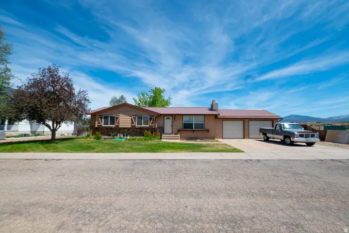 Ranch-style exterior with a metal roof, attached two-car garage, and a concrete driveway