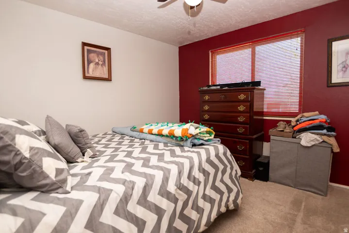 Bedroom featuring light colored carpet, ceiling fan, and a textured ceiling