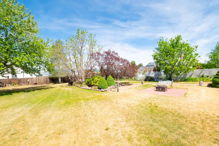 Expansive rear yard featuring a red brick patio, established landscaping, and mature trees