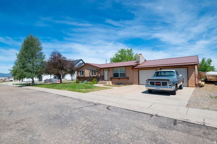 Single-story residence featuring a metal roof, attached two-car garage, and a concrete driveway