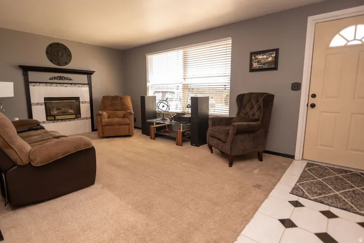 Living room featuring a tiled fireplace, light tile patterned floors, and light carpet