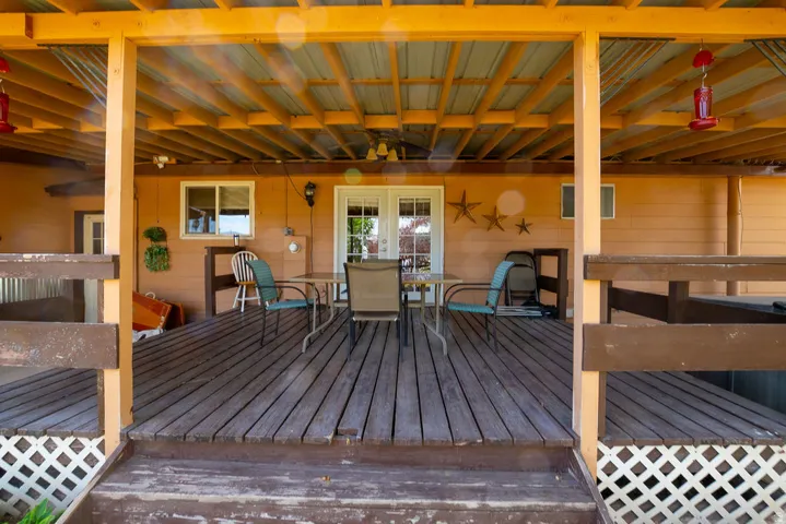 Expansive covered deck featuring wood plank flooring, a metal roof, and a perimeter railing with lattice accents