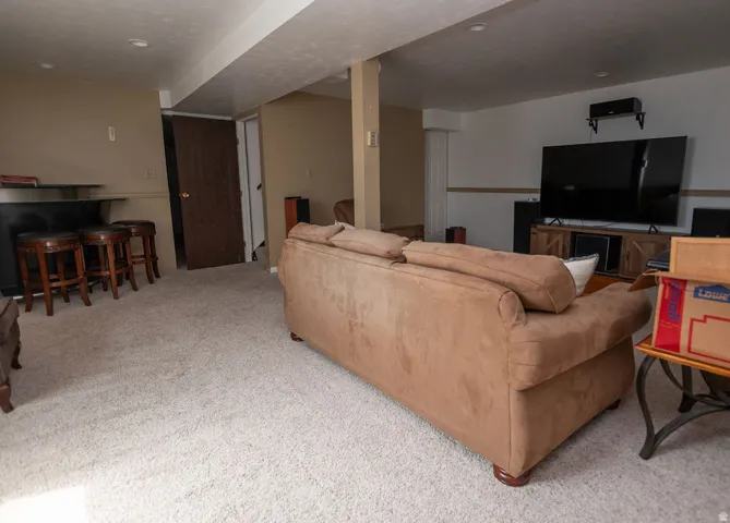 Living room featuring light colored carpet and a bar