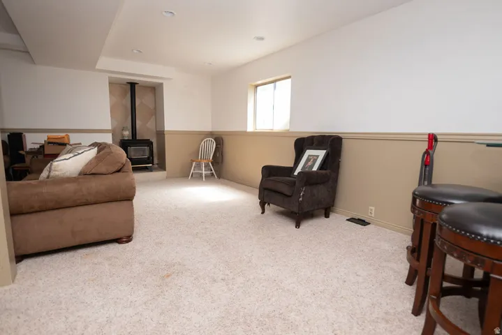 Living area with a wood stove, light carpet, and recessed lighting
