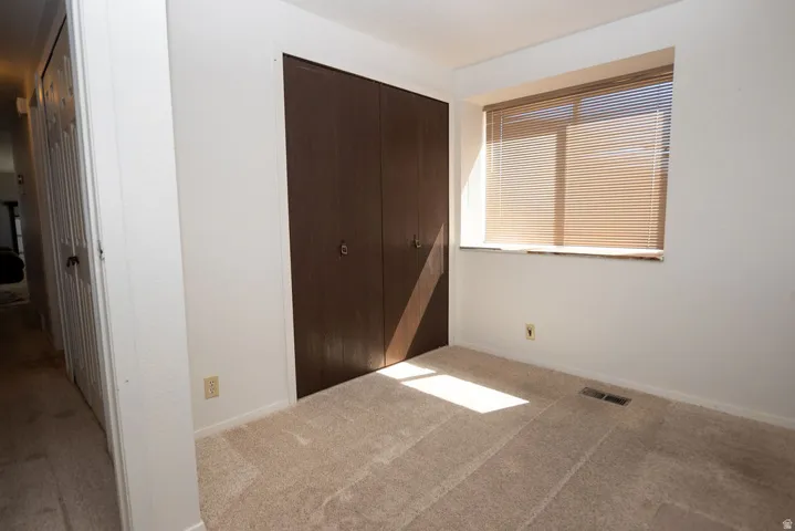 Unfurnished bedroom with light colored carpet and a closet