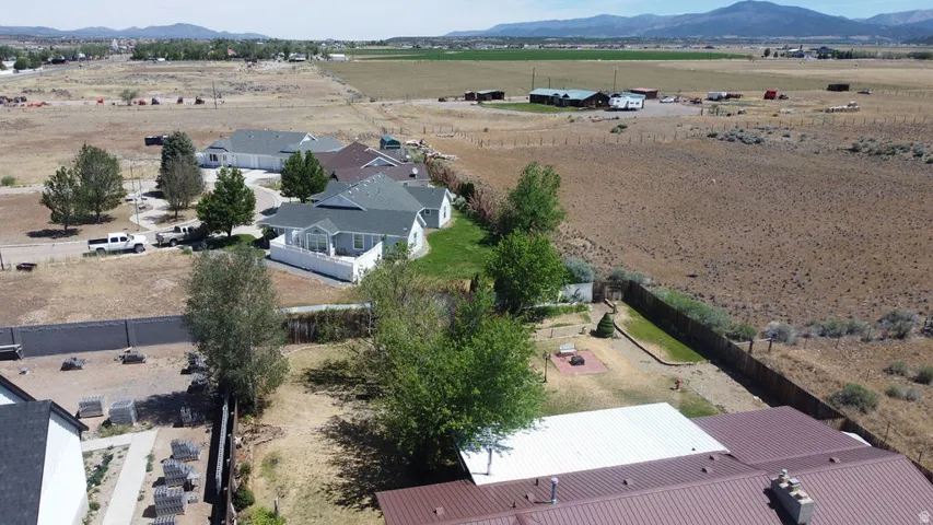 Aerial perspective showcasing multiple properties, including a residence with a light gray roof and a brown metal roof structure