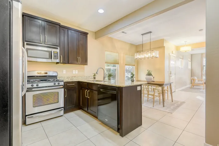 Kitchen featuring stainless steel appliances, a peninsula, dark wood finish cabinetry