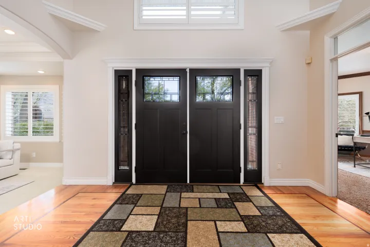 Foyer entrance with light wood-style flooring, ornamental molding, and arched walkways