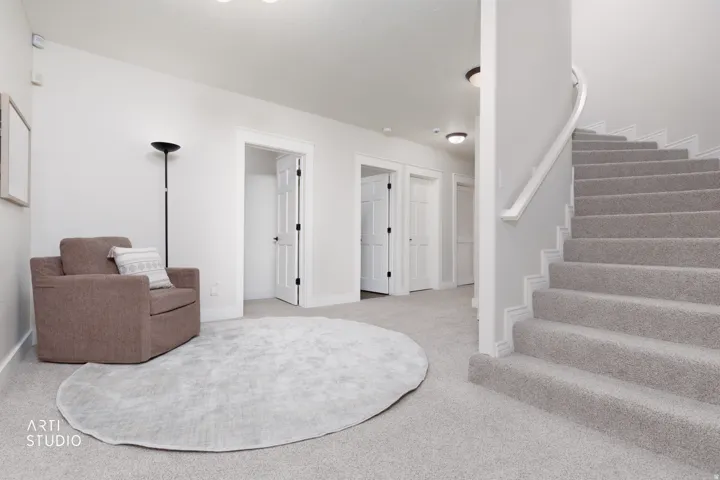 Sitting room with stairs and light colored carpet
