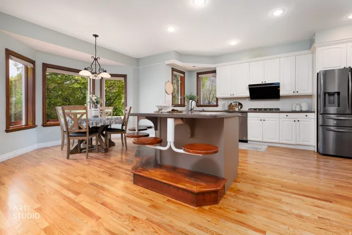 Kitchen with dark countertops, tasteful backsplash, stainless steel appliances, a kitchen bar, and white cabinets