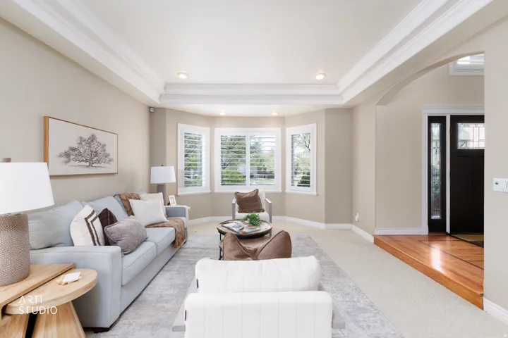 Living room featuring a tray ceiling, arched walkways, crown molding, recessed lighting, and light colored carpet