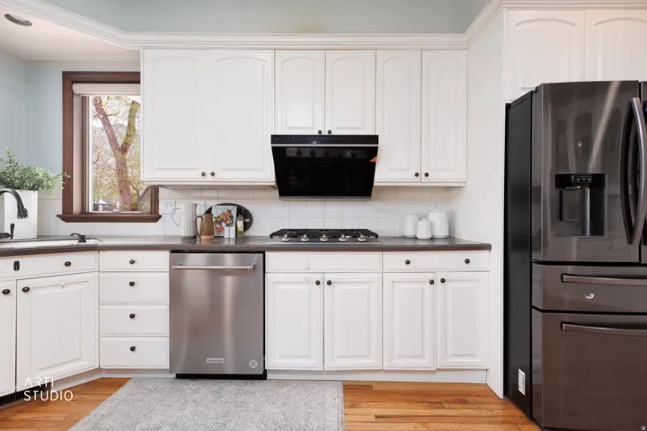 Kitchen featuring stainless steel appliances, white cabinets, decorative backsplash, and light wood-style flooring