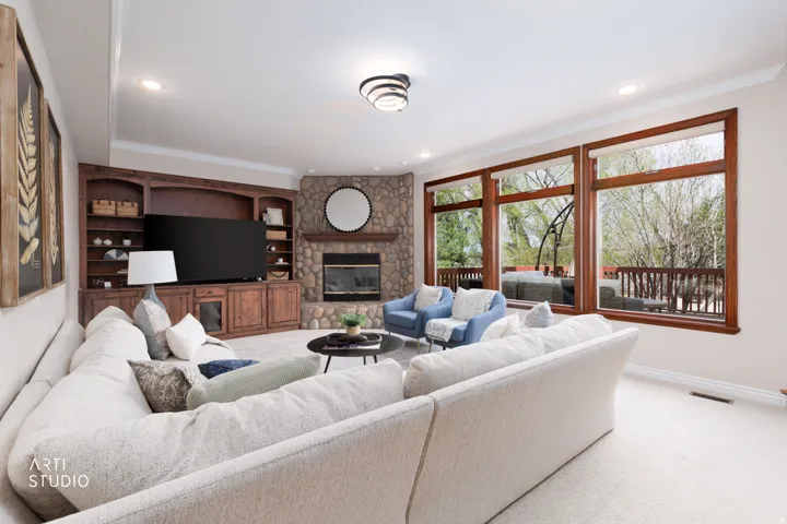 Living area with a stone fireplace, carpet flooring, crown molding, and recessed lighting